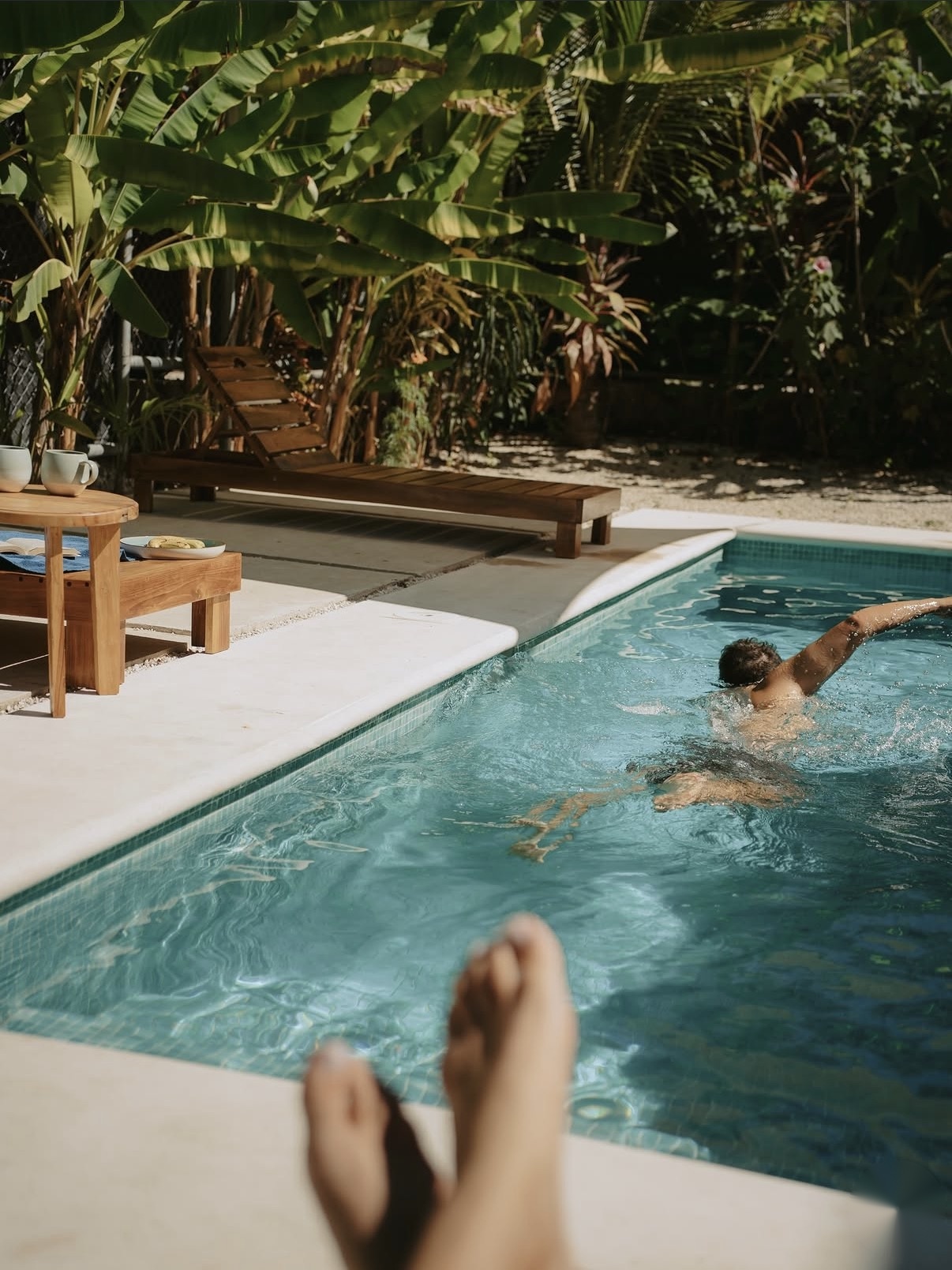 Guest swimming in the accommodation pool surrounded by tropical plants