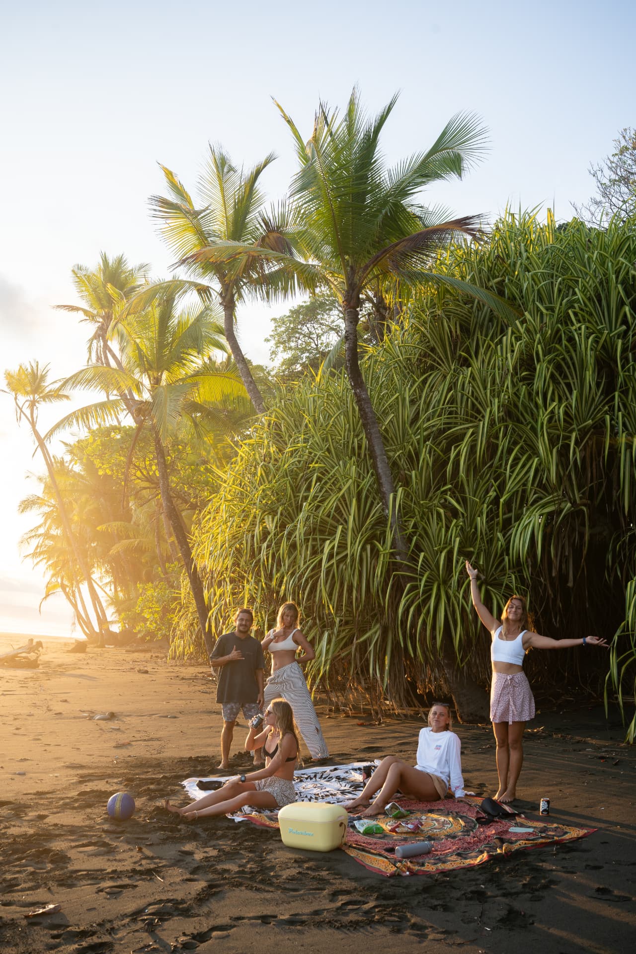 Kahu Surf Club guests gathered on the sand at golden-hour sunset
