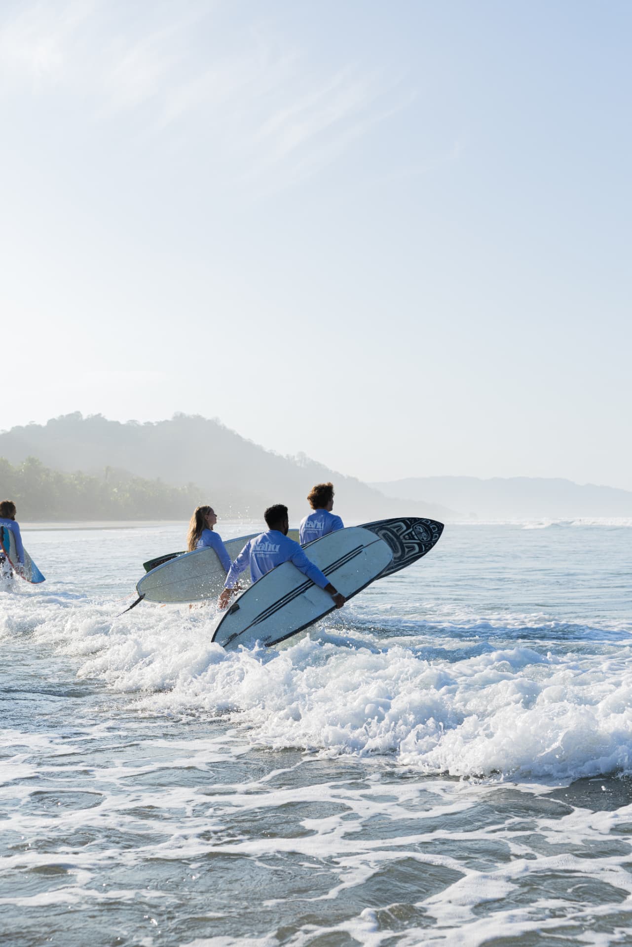 Kahu Surf Club coaches and guests walking into the water with their boards