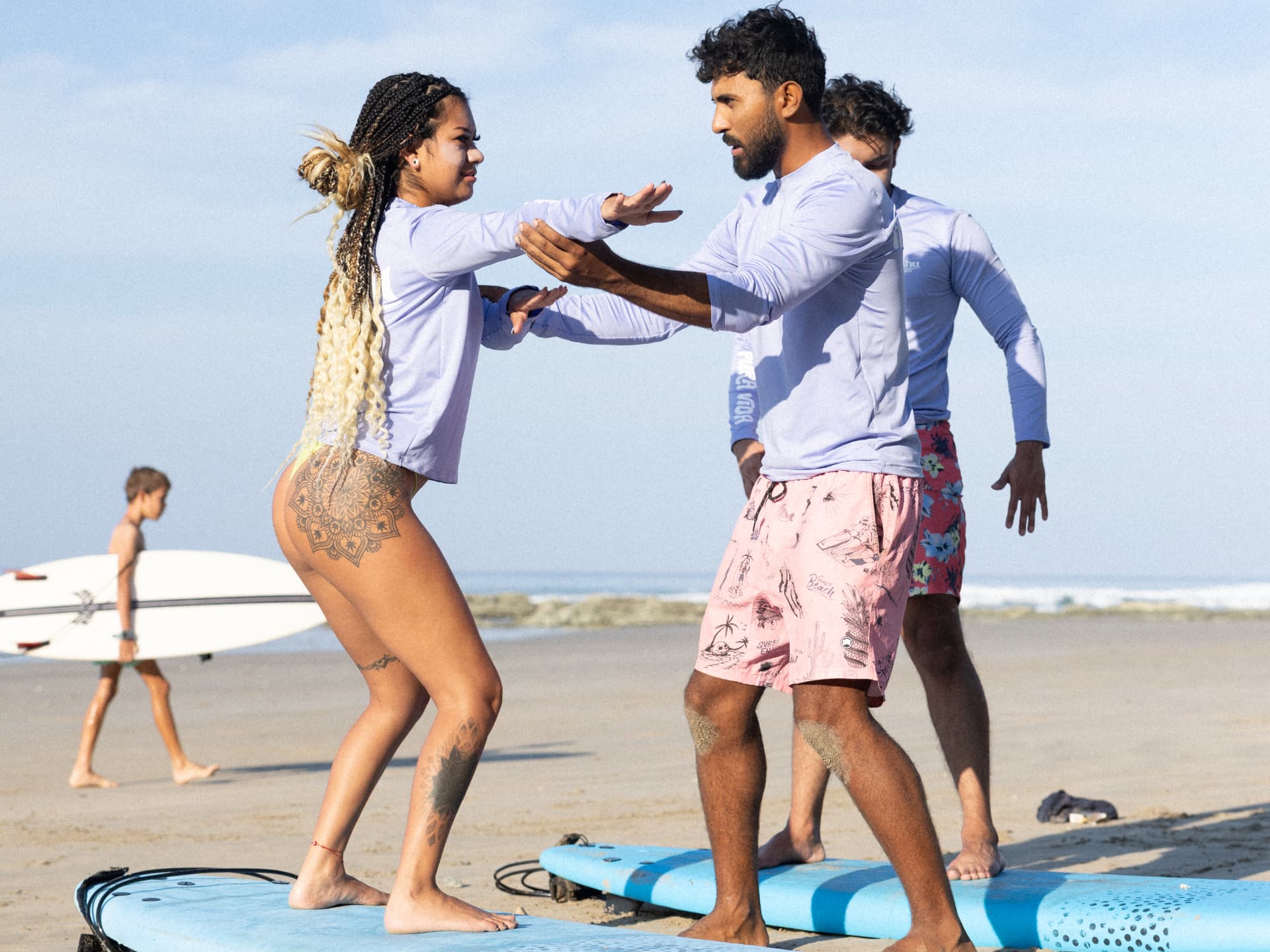 Surf coach guiding a surfer's stance during a beach lesson